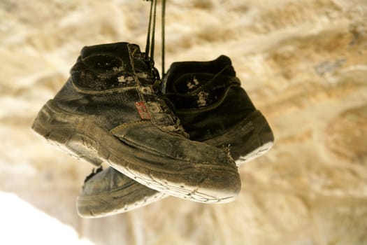 Construction worker left his aged old boots away, hunged on the rocks