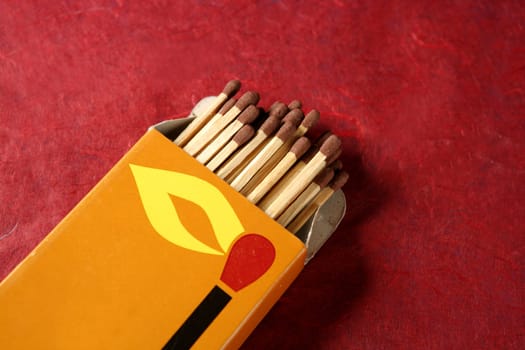 Wooden matches in a box over red background