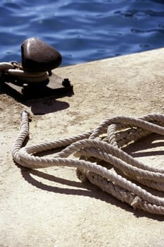 Boat bollard, ropes and knots in mediterranean harbor, macro detail