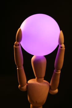 wooden mannequin holding a pink light ball over head