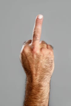 Hairy man hand closeup obscene expression over gray background