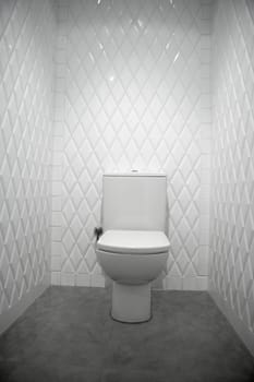 toilet in a white narrow room diamond shape tiles
