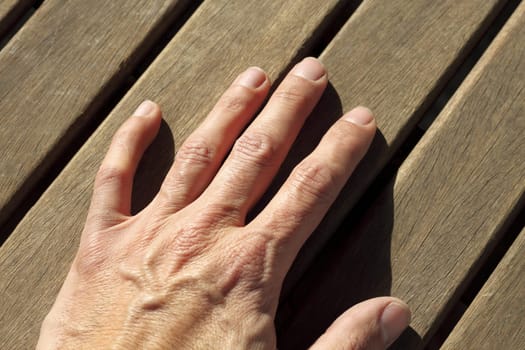 man hand over sunny teak tropical wood lines horizontal image