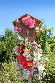 Virgin Christian Catholic religion sacred icon figurine with flowers outdoor