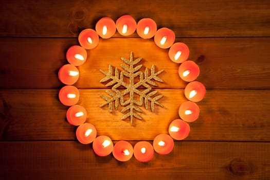 christmas candles circle over wood and golden snowflake symbol