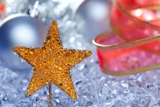 christmas golden star symbol with silver baubles and red ribbon on ice