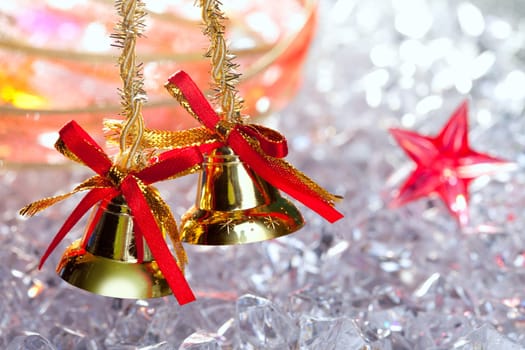 christmas golden bells with red ribbon on winter ice and stars