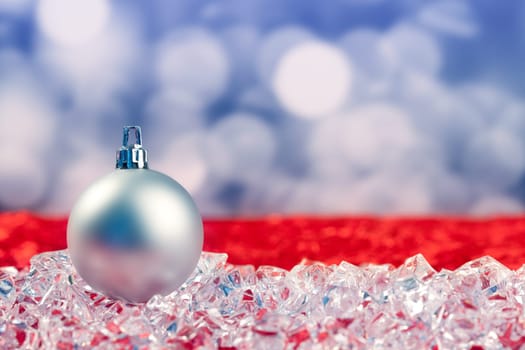Christmas silver bauble on ice cubes with blue lights bokeh background