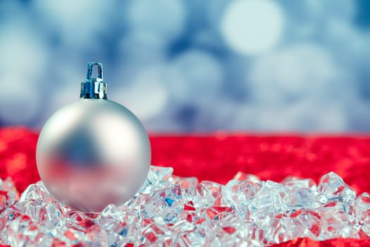 Christmas silver bauble on ice cubes with blue lights bokeh background