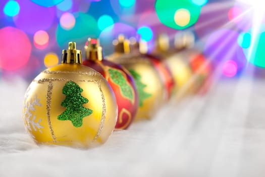 christmas golden red baubles in a row with colorful lights background