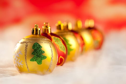 christmas golden red baubles in a row with colorful lights background