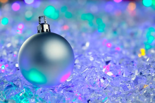 christmas silver bauble on colorful glowing ice cubes