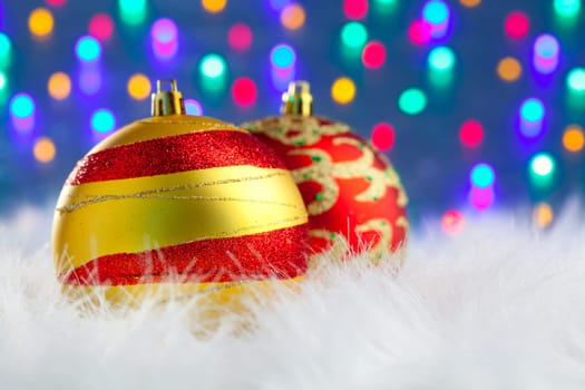 christmas baubles on white fur and colorful lights