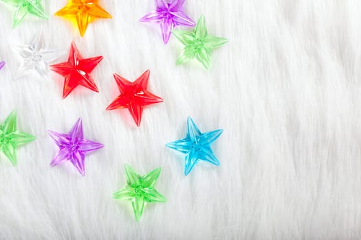 christmas colorful glass stars over white fur background as snow