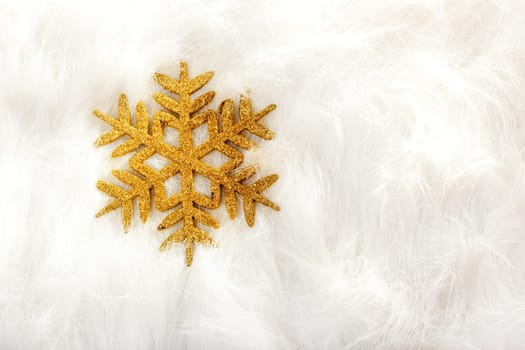 Christmas golden snowflake over white fur background