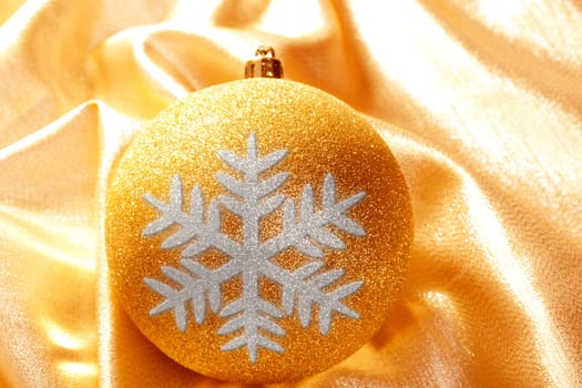Christmas glitter snowflake bauble on golden fabric background