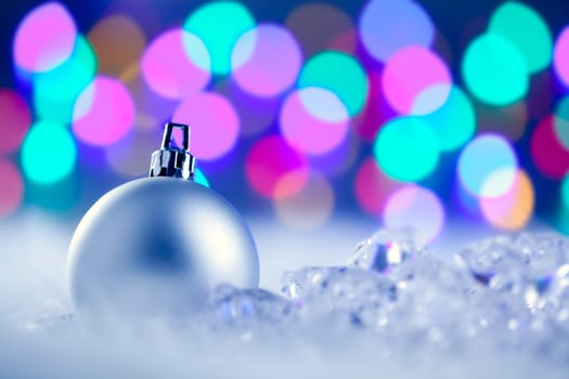 Christmas silver bauble in colorful blurred lights background