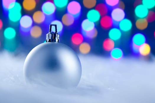 Christmas silver bauble in colorful blurred lights background