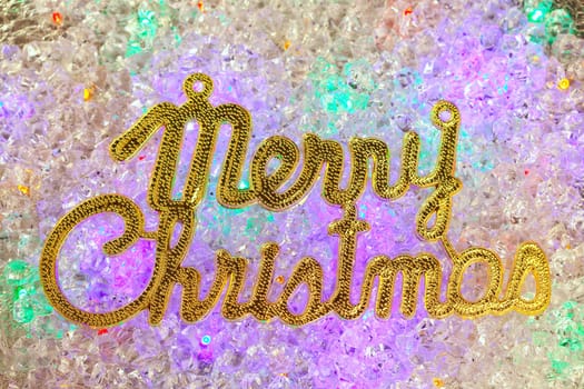 Merry christmas written in gold over colorful ice cubes
