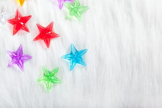 christmas colorful glass stars over white fur background as snow