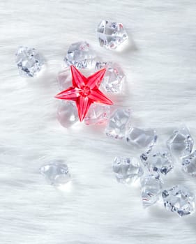 christmas red crystal star over ice cubes and white fur background