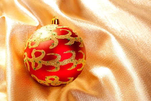 Christmas red bauble on golden  fabric background