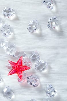 christmas red crystal star over ice cubes and white fur background