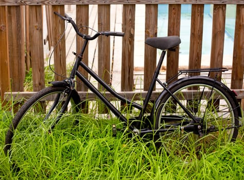 black grunge bicycle aged on a wood fence and grass