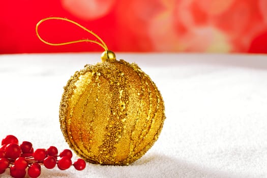 Christmas card of golden bauble berries on snow and red background