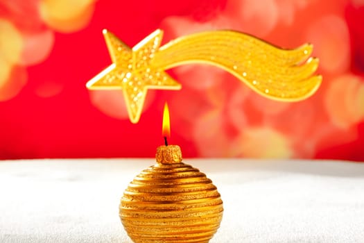 Christmas golden candle and bethlehem comet star on snow and red