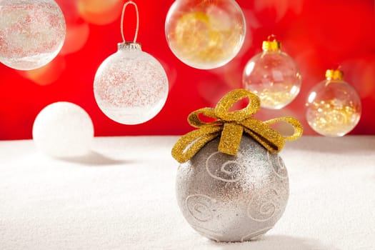Christmas silver bauble with golden loop on snow red background