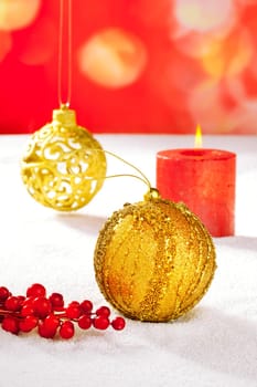 Christmas card of golden baubleand candle on snow