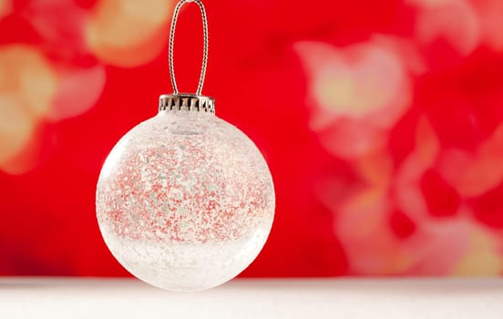 Christmas glass transparent bauble on snow and red background