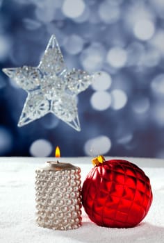 Christmas card of silver star bauble and candle on snow and blue background