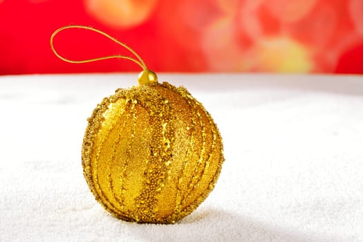 Christmas golden bauble on snow and red background