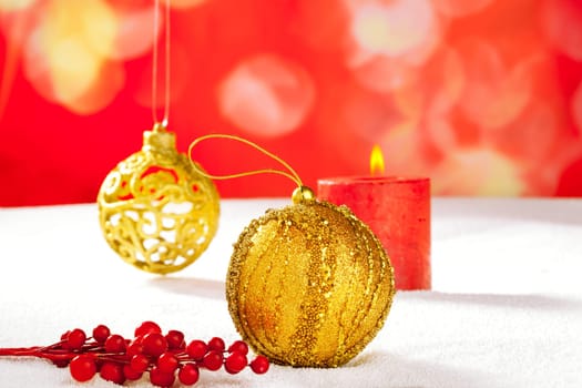 Christmas card of golden baubleand candle on snow