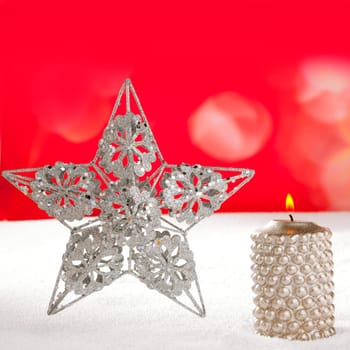 Christmas card of silver star and candle on snow and red background