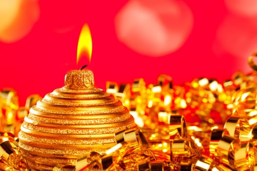 Christmas card of golden bauble candle on gold tinsel and red background