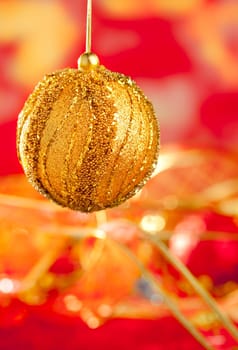 Christmas card of golden bauble and red blur background