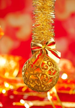 Christmas card tinsel golden glitter bauble ribbon loop on red blur background