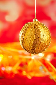 Christmas card of golden bauble and red blur background