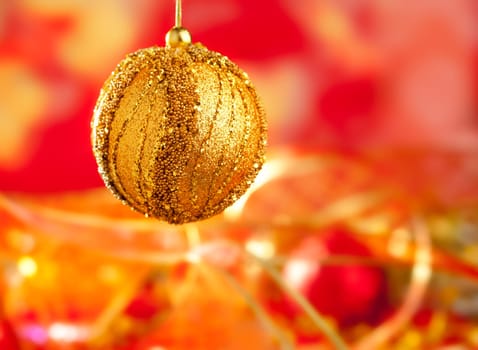 Christmas card of golden bauble and red blur background