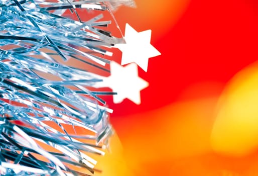 Christmas card tinsel stars silver blue on red blurred background