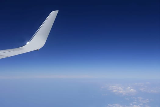 Aircraft wing detail flying high up in deep blue sky