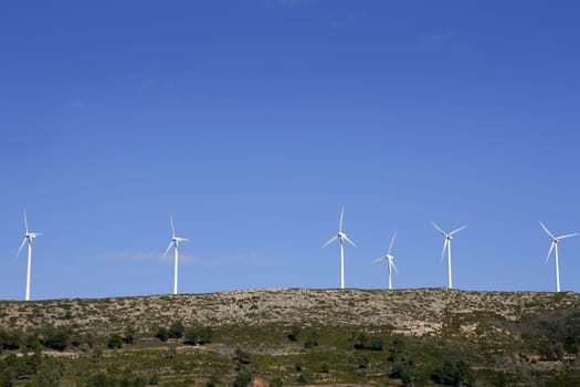 Top of mountain with windmills in Spain over blue sky