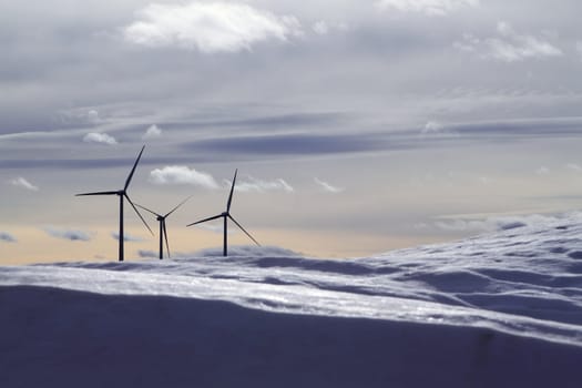 aerogenerator electric windmills snow mountain blurred foreground