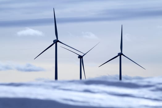aerogenerator electric windmills snow mountain blurred foreground