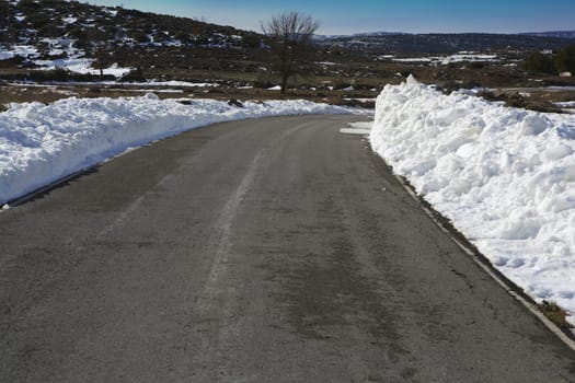 asphalt road curve with snow in both side borders
