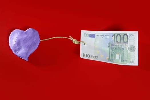 Love and money metaphor with purple plasticine heart and euro note