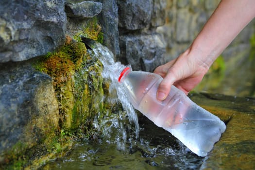 source of spring water bottle filling holding hand in Pyrenees mountain